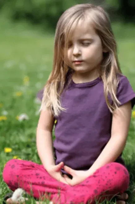 A child meditating in a field